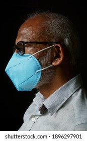 Portrait Of 60 Years Old Indian Man Wearing A Blue Mask, Isolated On A Black Background, In Order To Protect Himself From COVID-19.