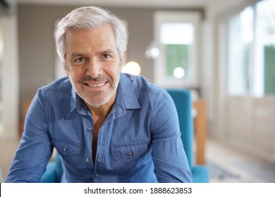 Portrait of 60-year-old man with grey hair and blue shirt looking at camera