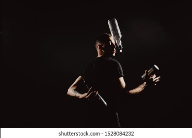 Portrait In Action. Young Handsome Male Bartender Making Cocktail I Dramatic Lightinig. Barmen Juggling Performance With Shaker And Bottle Isolated On Black