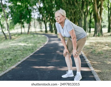 Portrait of an active beautiful senior woman tired and exhausted resting  and making a break after exercicing outdoors in park - Powered by Shutterstock