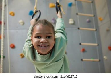 Portrait Of Active Black Child Hanging On Sports Rings At Home And Smiling At Camera, Copy Space