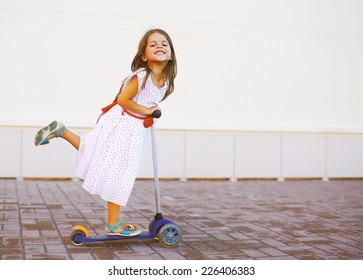 Portrait Of Active Little Girl Child Skating On Scooter In The City