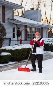 Portrait Of Active Senior Citizen With Snow Shovel In Front Of House (Vertical)