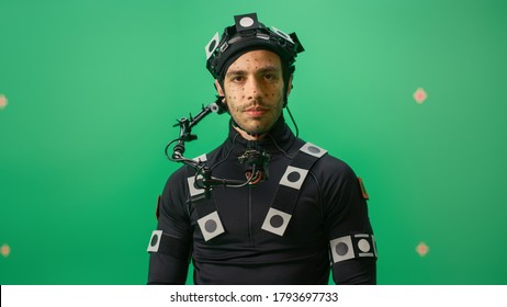 Portrait of an Actor Wearing Motion Caption Suit and Head Rig Posing with Green Screen Background. Film Studio Set Shooting Blockbuster Movie with Chroma Key. Medium Shot Looking at Camera - Shutterstock ID 1793697733