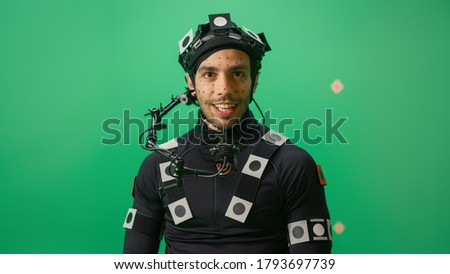 Portrait of an Actor Wearing Motion Caption Suit and Head Rig Posing with Green Screen Background. Big Budget Filmmaking On Film Studio Set Shooting Blockbuster Movie with Chroma Key.