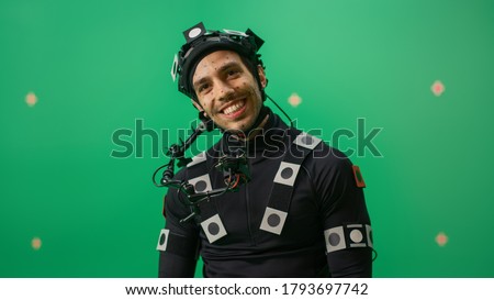 Portrait of an Actor Wearing Motion Caption Suit and Head Rig Posing with Green Screen Background. Film Studio Set Shooting Blockbuster Movie with Chroma Key.