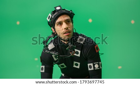 Portrait of an Actor Wearing Motion Caption Suit and Head Rig Posing with Green Screen Background. Big Budget Filmmaking On Film Studio Set Shooting Blockbuster Movie with Chroma Key.
