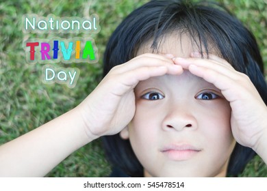 Portrait of adorable Asia child girl on grass field with her hand on eyebrows as looking for answer with word National Trivia day on January 4th. - Powered by Shutterstock