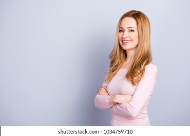 Portrait Of Adorable Attractive Confident Mature Cheerful Woman With Long Blonde Wavy Hair Wearing Light Pink Blouse Keeping Arms Crossed Isolated On Gray Background