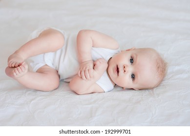 Portrait Of Adorable Baby Boy Lying On The Bed On His Side