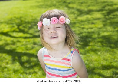 Portrait Of Adorable Blond Young Girl In Preschool Age Wearing Flowers In Hairs Outdoors Enjoying Sun On Swedish Midsummer Celebration