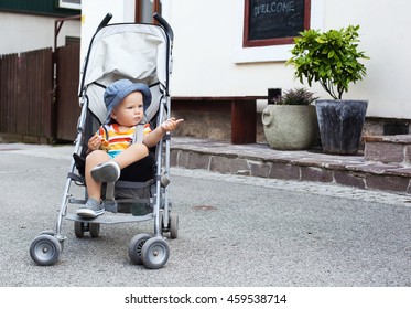 Portrait of adorable a child in a stroller on the street. Bled, Slovenia. European streets, summer atmosphere, leisure and travel.