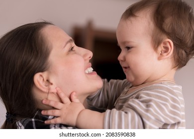 Portrait Adorable Face Of Little Cheerful Happy Toddler Baby Girl Child With Charming Smile Look At Mom Strong Cuddles Loving Mommy Together. Mother Hugs Play Love Care Kiss Smiling Daughter At Home