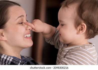 Portrait Adorable Face Of Little Cheerful Happy Toddler Daughter Baby Charming Smile Look At Mom Strong Cuddles Loving Mommy Together. Child Catches Holding Mom By Nose Sincere Feelings Love Care