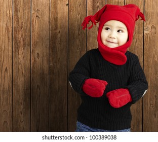 Portrait Of An Adorable Kid Smiling Wearing Winter Clothes Against A Wooden Background