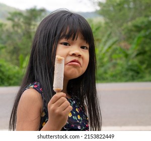 Portrait Of An Adorable Little Asian Girl With Long Black Hair Dress Casual Holding Ice Cream. Focus On A Girl Face. Happy And Holiday Concept.