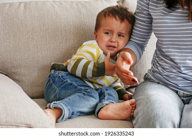 Portrait Of Adorable Little Boy Sitting On The Textile Couch With His Mom And Crying. Upset Toddler Throwing A Tantrum At Home. Barefoot Kid Calling For Attention. Close Up, Copy Space, Background.