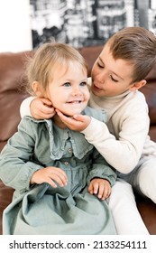 Portrait of adorable little brother and sister sitting on chair, hugging and smiling. Cute stylish dressed small kids having fun, playing together and laughing, childhood concept. High quality photo - Shutterstock ID 2133254111