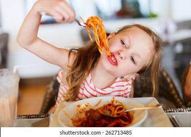 Portrait Of Adorable Little Girl Eating Spaghetti For A Lunch At Restaurant