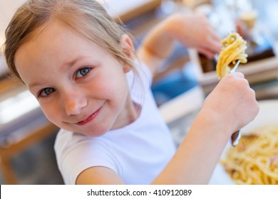 Portrait Of Adorable Little Girl Eating Spaghetti For A Lunch At Restaurant