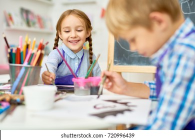 Portrait of adorable little girl smiling happily while enjoying art and craft lesson in pre school working together with boy