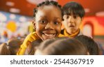 Portrait of an Adorable Stylish Black Girl Posing, Looking at Camera and Smiling. Cheerful African Child Spending Productive Time in Daycare, Playing Alone with Colorful Building Blocks