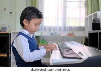 Portrait Of Adorable Young Asian Kid Practicing The Piano Alone At Home