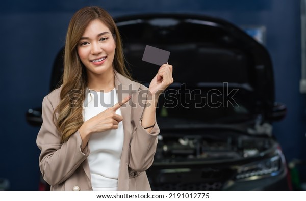 Portrait adult beautiful Asian female customer\
smiling, satisfied, positive evaluation with car maintenance\
service, showing, holding, using credit card for payment. Service,\
Industry Concept