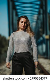 A Portrait Of An Adult Caucasian Woman Wearing A Sheer Shirt With Black Trousers And Posing Outdoors