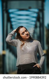 A Portrait Of An Adult Caucasian Woman Wearing A Sheer Shirt With Black Trousers And Posing Outdoors