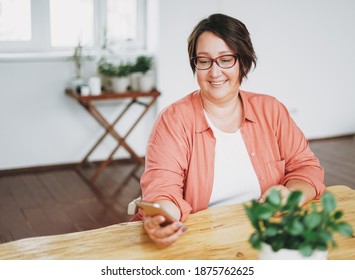 Portrait of adult charming brunette woman businesswoman in glasses plus size body positive using mobile at home office - Powered by Shutterstock