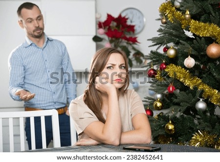 Portrait of adult couple quarreling at home near table with Christmas dinner