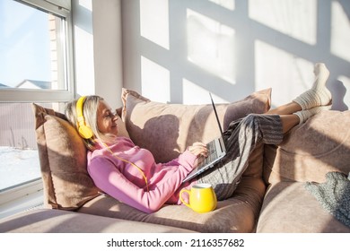 Portrait Of Adult Happy Female Freelancer Sitting On The Couch And Working On Project, Watching Movie On Laptop, Studying, Blogging, Resting And Chatting Online. Lady At Home