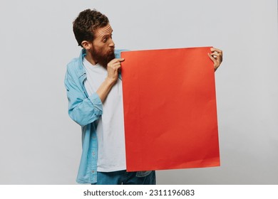 Portrait of an adult male on a gray background with a red piece of paper for your design and text, layout, copy space, space for text - Shutterstock ID 2311196083