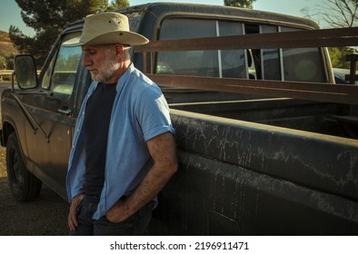 Portrait Of Adult Man In Cowboy Hat Standing Against A Vintage Truck During Sunset