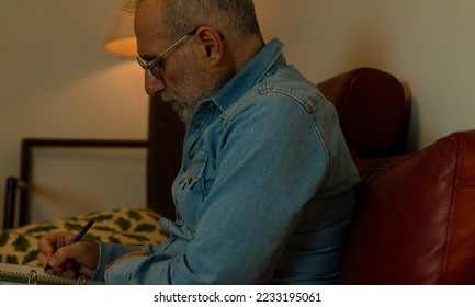 Portrait of adult man sitting on sofa at home and reading document files. - Shutterstock ID 2233195061