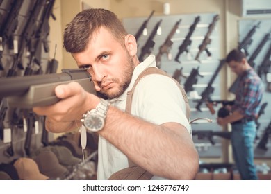 Portrait of adult man which is choosing air-powered gun in army market. - Shutterstock ID 1248776749