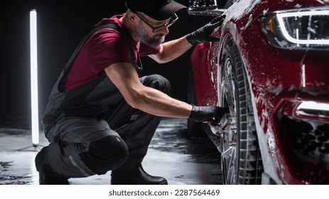 Portrait of an Adult Man Working in a Detailing Studio, Prepping a Factory Fresh American Sportscar for Maintenance Work and Car Care Treatment. Cleaning Technician Using Sponge to Wash the Wheels - Powered by Shutterstock