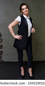 Portrait Of Adult Pretty Woman 40 Years Old In A Business Suit On A Gray Background. Business Concept. Standing Right In Front Of The Camera With A Serious Mood.