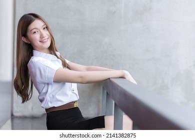 Portrait Of An Adult Thai Student Girl In University Student Uniform. Asian Beautiful Girl Sitting Smiling Happily At University