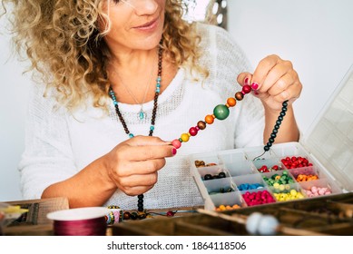 Portrait of adult woman creating beads bracelets and necklace at home for new modern and trendy business - people spent time at home doing hobby or alternative job concept