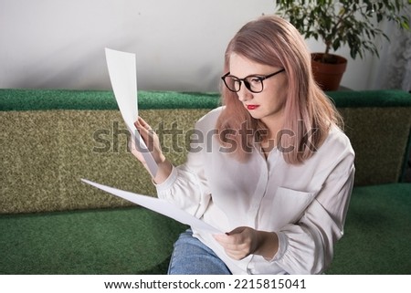 Portrait of an adult woman entrepreneur with grayish hair in a managerial position, dressed in a white blouse and busy working in the office