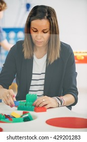 Portrait Of Adult Woman Playing With Lego Blocks At Table