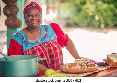 Portrait of an adult woman standing in her kitchen looking at a camera. Proud African American woman in colorful Garifuna dress. - Shutterstock ID 2188675821