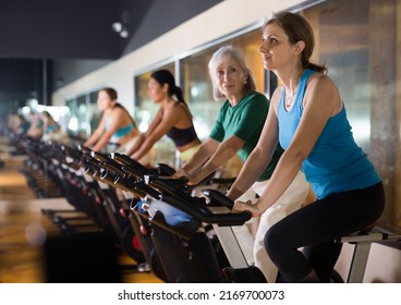 Portrait of adult woman training on stationary bike workout in gym - Powered by Shutterstock