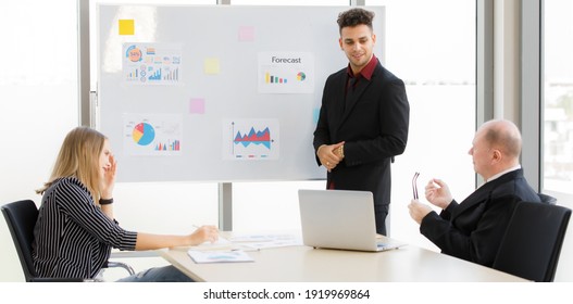 Portrait of adults caucasian 1 business manager briefing with staff team in the morning. Meeting have 1 businessman and 1 woman listening. On table have laptop, paper and paper graph chart background. - Shutterstock ID 1919969864