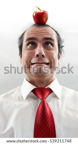portrait of an afraid executive with apple on the head with red necktie and white shirt 
