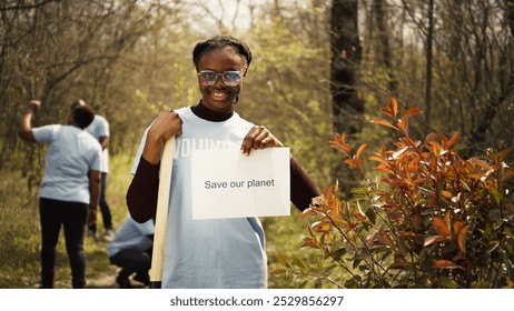 Portrait of african american activist holding poster with save our planet message, spread environmental care and awareness. Young woman posing with banner to fight ecological justice. Camera B. - Powered by Shutterstock