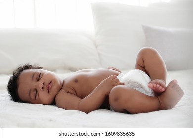 portrait of african american baby girl sleeping on white bed