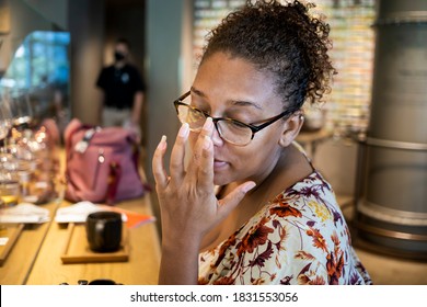 Das Porträt einer schwarzen Afroamerikanerin mit Brille sitzt glücklich im Kaffeehaus. sie trägt ein buntes Kleid und wartet auf ihr Getränk.